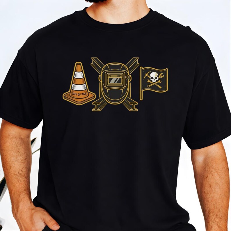 May include: Black t-shirt with a gold graphic featuring a traffic cone with "CITY OF PGH" text, a welding mask, and a pirate flag with a skull and crossbones. The design is centered on the chest.