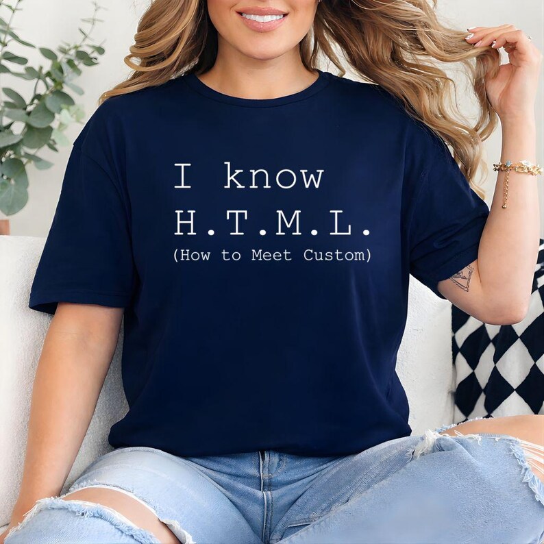 Pode incluir: Uma t-shirt azul-marinho de manga curta com texto em branco que diz: I know H.T.M.L. (How to Meet Custom). A pe&ccedil;a tem gola redonda e um corte padr&atilde;o, exibindo o gr&aacute;fico impresso claramente no centro da &aacute;rea do peito.