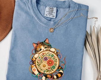 T-Shirt mit Katzenmotiv, ideal für Stickbegeisterte und Katzenliebhaber. Perfekt als Geschenk für Kreuzstich-Fans und Stickbegeisterte. Auch geeignet für alle, die gerne mit Blumenstickereien arbeiten.