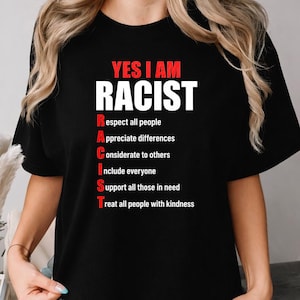Może przedstawiać: Czarny t-shirt z czerwono-białym napisem YES I AM RACIST, po którym następuje lista akronimów: Respect all people, Appreciate differences, Considerate to others, Include everyone, Support all those in need, Treat all people with kindness.