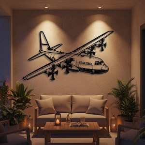 Pode incluir: Uma obra de arte de parede em metal preto que retrata um avião C-130 Hercules, com as palavras "U.S. AIR FORCE" visíveis. A obra de arte é montada em uma parede de cor clara, iluminada por holofotes, e faz parte de um espaço de convivência ao ar livre.