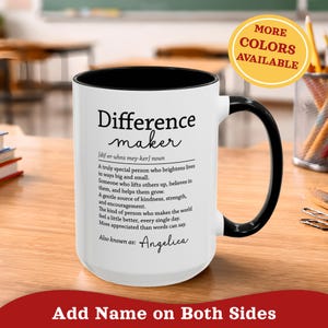 Può includere: Tazza in ceramica bianca con interno e manico neri. La tazza presenta il testo "Difference maker" con una definizione e il nome "Angelica". Un cerchio giallo indica che sono disponibili più colori.