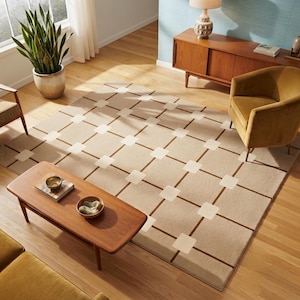 May include: A rectangular area rug featuring a grid pattern of light beige squares connected by thin dark brown lines. The rug is positioned on a light wood floor in a room containing a wooden coffee table, a mustard yellow armchair, and a plant.