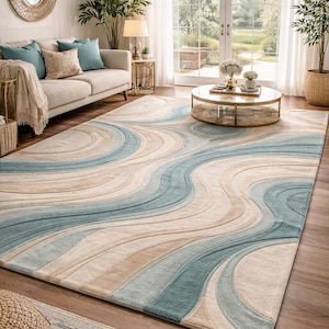 May include: A large area rug with a flowing, wave-like design in shades of blue, beige, and cream. The rug is the focal point of a living room, complementing the neutral-toned furniture and decor.