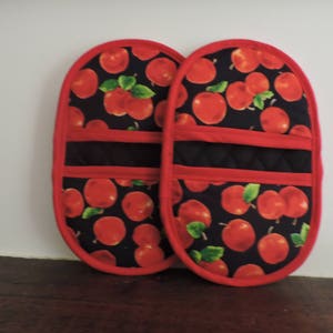 May include: A pair of red and black oven mitts with a red apple print. The mitts have a quilted black lining and a red trim.