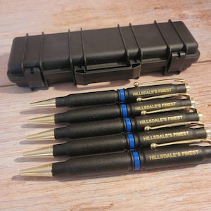May include: Six black pens with gold accents and blue trim. Each pen has the words "HILLSDALE'S FINEST" engraved in gold lettering. The pens are in a black hard case.