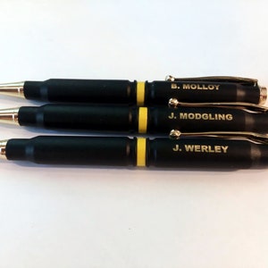 May include: Three black and gold bullet-shaped pens with personalized names: B. Molloy, J. Modgling, and J. Werley.
