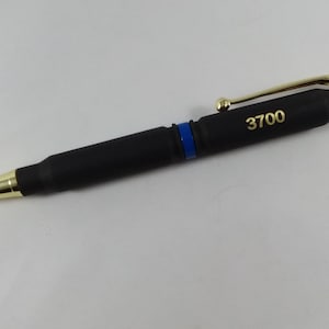 May include: A black pen with a gold clip and tip. The pen is shaped like a bullet and has a blue stripe. The number 3700 is engraved on the pen.