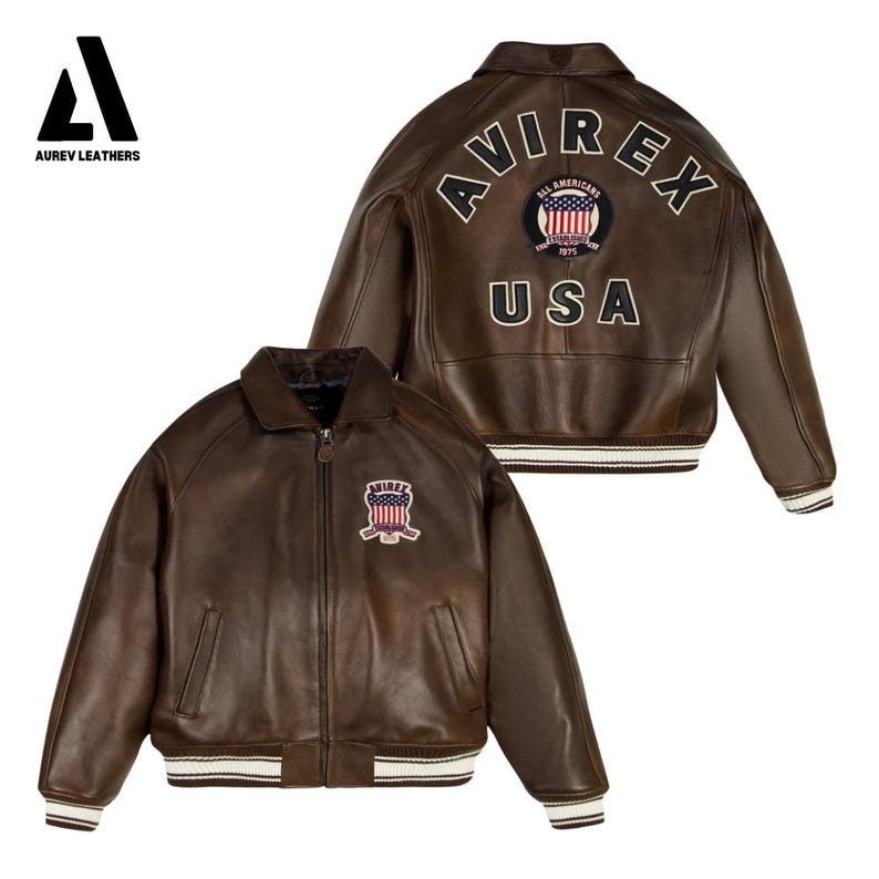 May include: Brown leather jacket with the text "AVIREX" and "USA" on the back, along with a patch featuring the American flag. The jacket has a zip-up front, a collar, and white and brown striped cuffs and hem.