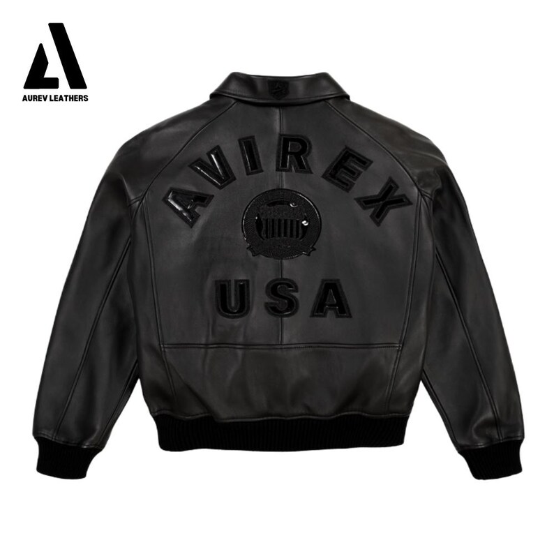 Puede incluir: Chaqueta de cuero negra con el texto "AVIREX USA" en la espalda. La chaqueta tiene cuello, pu&ntilde;os y dobladillo de canal&eacute;. El logotipo de Aurev Leathers est&aacute; en la esquina superior izquierda.