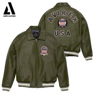 May include: Olive green leather jacket with the text "AVIREX" and a USA patch on the back. The jacket has a collared neckline, a zipper closure, and a patch on the chest. The cuffs and hem feature white stripes.