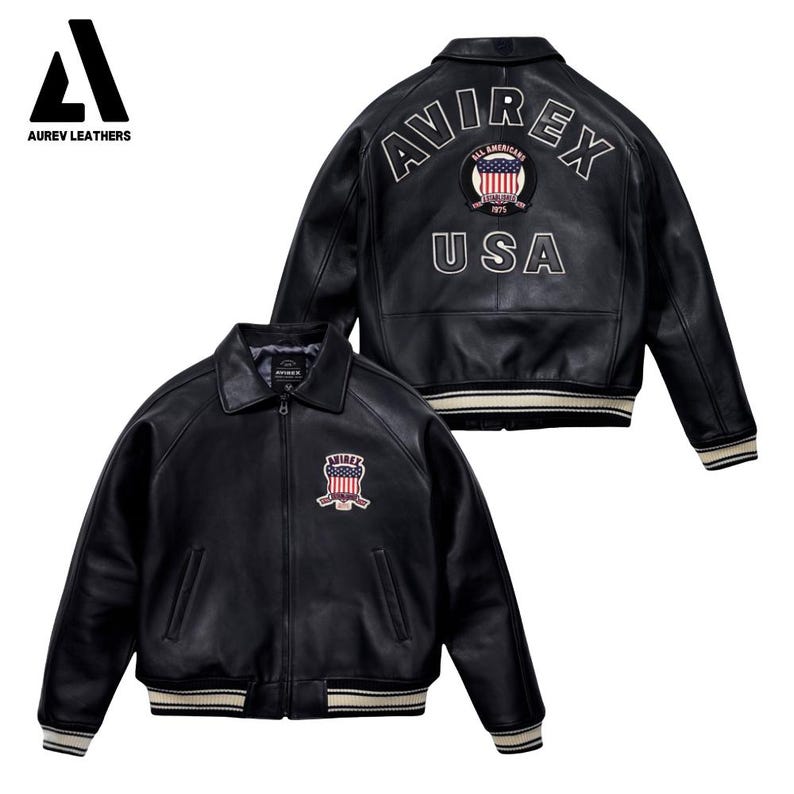 May include: Black leather jacket with a classic collar and a zip-up front. Features the text "AVIREX" and "USA" on the back, along with a patch on the chest. The jacket has white and beige striped trim on the cuffs and hem.