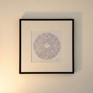 Peut inclure: Œuvre d'art encadrée avec un motif circulaire composé de formes géométriques bleues. L'œuvre est encadrée dans un passe-partout blanc et un cadre noir, accrochée à un mur blanc. Une pièce abstraite moderne pour la décoration.