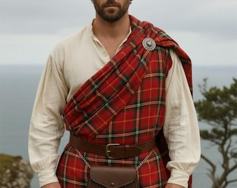 May include: A man in traditional Scottish attire, featuring a red and green plaid kilt and matching shawl. He wears a white shirt, brown leather belt, and a sporran. A silver brooch secures the shawl.