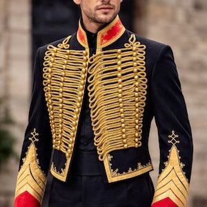 Può includere: Giacca nera in stile militare con dettagli in corda dorata e bottoni dorati. La giacca ha accenti rossi sul colletto e sui polsini. Le maniche presentano strisce dorate a forma di gallone. Fa parte di un abito formale.