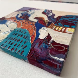 以下が含まれることがあります： 厚い筆致の正方形の抽象画。この作品は、青、オレンジ、紫、白のパレットを使用したテクスチャのある表面が特徴です。この絵画は、目に見えるペイントのテクスチャとダイナミックな構成を備えた、モダンで表現力豊かなスタイルです。