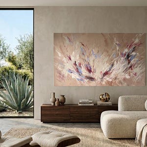 May include: An abstract painting with a beige background and dynamic brushstrokes in white, purple, and blue hues. The artwork hangs above a dark wood cabinet with decorative vases and books. A modern living room setting.