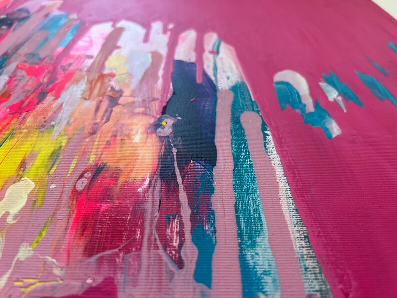 May include: Abstract art piece with a vibrant color palette. The artwork features a bright pink background with streaks of teal, white, yellow, and dark blue paint. The paint appears to be dripping down the canvas, creating a dynamic visual effect.