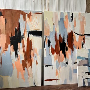 May include: Three rectangular canvases featuring abstract paintings with a palette of terracotta, black, light blue, and cream. The artwork displays vertical brushstrokes and layered colour blocks, creating a textured composition across the surfaces.