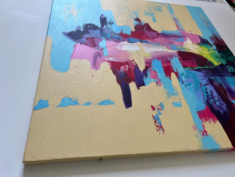May include: Abstract painting on canvas with a textured, beige background. Bold brushstrokes in shades of blue, pink, purple, red, and green create a dynamic composition. The artwork is mounted on a wooden frame.
