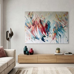 Pode incluir: Uma grande pintura retangular em tela com pinceladas abstratas em tons de vermelho, azul, azul-petr&oacute;leo e amarelo sobre um fundo branco. A obra exibe linhas din&acirc;micas e motivos circulares, criando uma sensa&ccedil;&atilde;o de movimento na superf&iacute;cie.