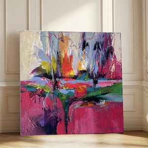 May include: An abstract painting with a vibrant color palette. The artwork features bold brushstrokes in shades of pink, red, blue, green, and yellow. The canvas is square and leans against a white wall and wooden floor.