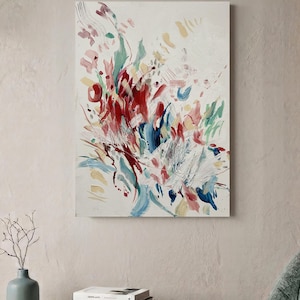 Op de afbeelding: Een rechthoekig schilderij op canvas met een abstracte compositie van energieke penseelstreken in tinten dieprood, zachtroze, gedempt blauw en lichtgeel tegen een getextureerde gebroken witte achtergrond, wat zorgt voor een dynamisch beeld.