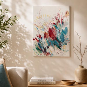 May include: A rectangular canvas wall art piece featuring an abstract painting with energetic brushstrokes in shades of deep red, teal, turquoise, and soft yellow on a cream-colored background, displayed vertically on a plain wall.
