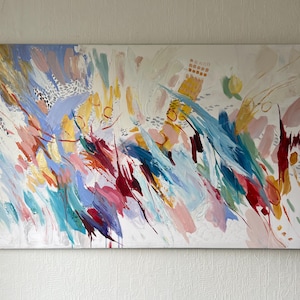 Puede incluir: Pintura abstracta con fondo blanco y pinceladas coloridas. La obra presenta salpicaduras de azul, rosa, amarillo y rojo, con toques de oro y plata. La pintura tiene una sensaci&oacute;n din&aacute;mica y en&eacute;rgica.