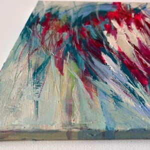 May include: Abstract painting on canvas with a textured surface. The artwork features a dynamic composition of brushstrokes in shades of red, blue, and white. The painting's edge is visible, showcasing the canvas's depth and construction.
