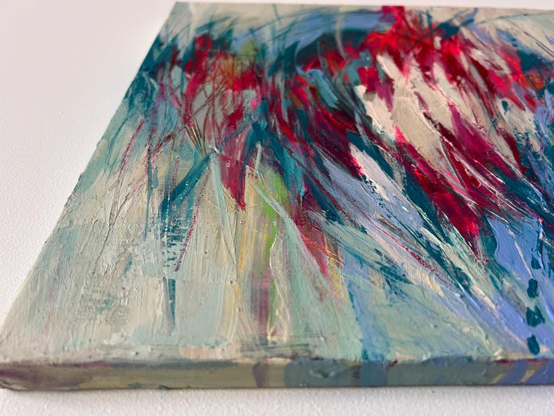 May include: Abstract painting on canvas with a textured surface. The artwork features a dynamic composition of brushstrokes in shades of red, blue, and white. The painting's edge is visible, showcasing the canvas's depth and construction.