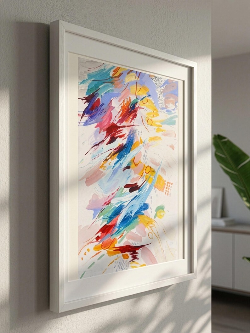 May include: A framed abstract painting featuring energetic brushstrokes in vibrant shades of red, yellow, blue, and soft pink against a cream background. The composition includes scattered circular motifs and fine line details within a white frame.