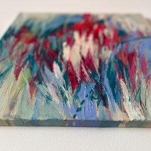 May include: Abstract painting on canvas with visible brushstrokes. The artwork features a textured surface with a palette of colors including red, blue, teal, and white. The painting has a square shape.