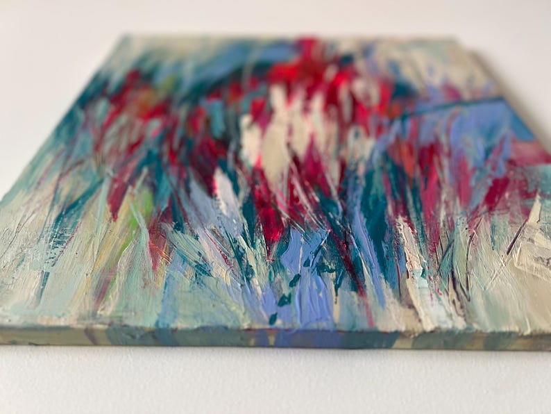 May include: Abstract painting on canvas with visible brushstrokes. The artwork features a textured surface with a palette of colors including red, blue, teal, and white. The painting has a square shape.