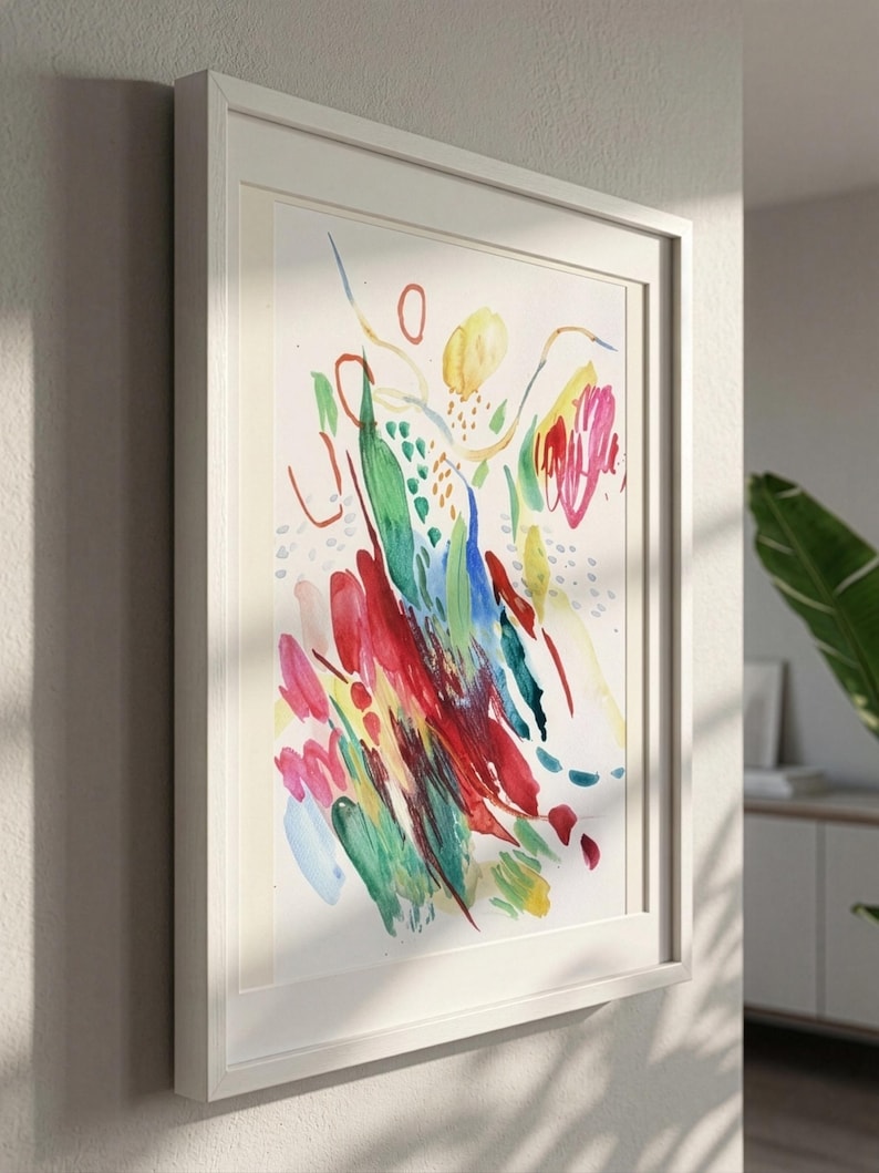 May include: A framed abstract painting featuring vibrant watercolor brushstrokes in shades of red, green, blue, and yellow on a white background. The artwork displays a variety of organic shapes, thin lines, and dotted patterns within a white frame.