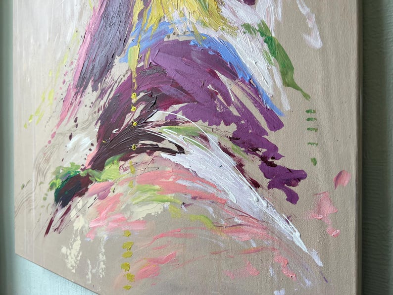 May include: Abstract painting on canvas with a neutral background. The artwork features bold brushstrokes in shades of purple, pink, white, yellow, blue, and green. The paint appears textured and layered, creating a dynamic and expressive composition.