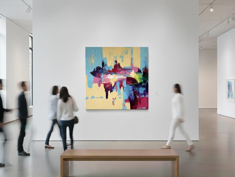 May include: An abstract painting with a light yellow background, featuring bold strokes of blue, red, and pink. The artwork is displayed in a modern art gallery setting, with blurred figures of people walking by.