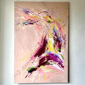 May include: Abstract painting on canvas with a beige background. The artwork features dynamic brushstrokes in shades of pink, purple, yellow, and blue, creating a sense of movement and energy. Splatter effects add texture to the piece.