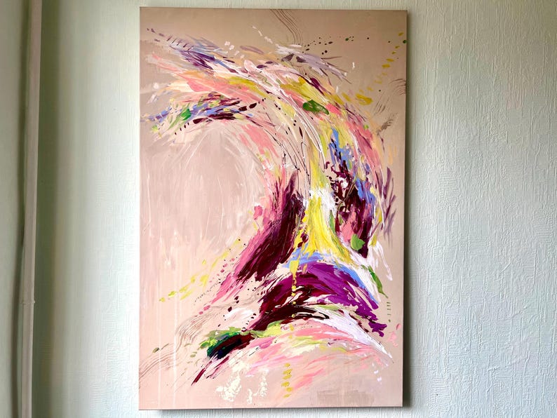 May include: Abstract painting on canvas with a beige background. The artwork features dynamic brushstrokes in shades of pink, purple, yellow, and blue, creating a sense of movement and energy. Splatter effects add texture to the piece.