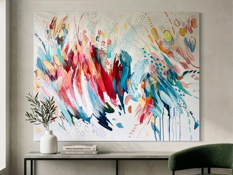 Pode incluir: Uma tela retangular grande apresentando uma pintura abstrata com pinceladas energ&eacute;ticas e amplas em tons vibrantes de vermelho, rosa, azul-petr&oacute;leo, azul e amarelo sobre um fundo branco, acentuado por pequenos pontos e linhas finas.