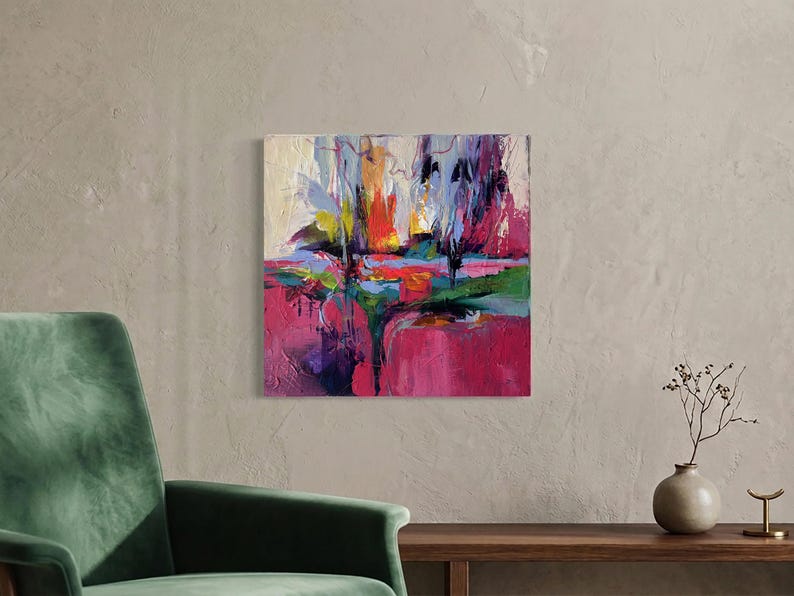 May include: An abstract painting with a textured surface. The artwork features bold brushstrokes in shades of pink, purple, green, yellow, and blue. The painting is mounted on a square canvas and hangs on a neutral-colored wall.
