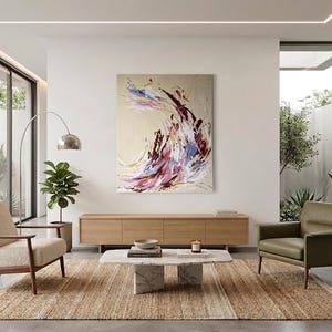 May include: A modern living room with a large abstract painting in shades of purple, blue, and red. The room features a light brown rug, two armchairs, a wooden cabinet, and a marble coffee table. A tall, arched lamp and potted plants add to the decor.