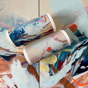 Puede incluir: Dos tubos cil&iacute;ndricos con un estampado abstracto vibrante con remolinos de azul marino, azul claro, rosa suave, naranja brillante y crema. Los tubos tienen tapas circulares blancas s&oacute;lidas en cada extremo, mostrando un dise&ntilde;o pintado din&aacute;mico.