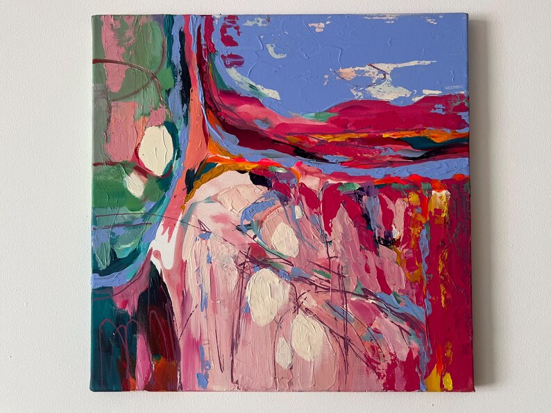 May include: Abstract oil painting on canvas with a palette of pink, red, blue, and green. The artwork features thick brushstrokes and a textured surface. White, oval shapes are scattered across the canvas, adding contrast to the vibrant colors. The painting is mounted on a square canvas.