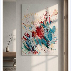 May include: A rectangular canvas painting featuring abstract brushstrokes in vibrant shades of red, teal, and yellow against a neutral off-white background. The composition includes dynamic lines, layered paint textures, and scattered marks.