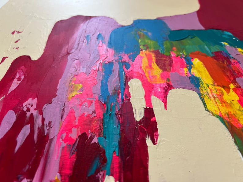 May include: Abstract artwork with bold brushstrokes in a variety of colours. The painting showcases pink, red, blue, yellow, and green shades, set against a creamy off-white backdrop. The textured paint application gives a dynamic and expressive feel.