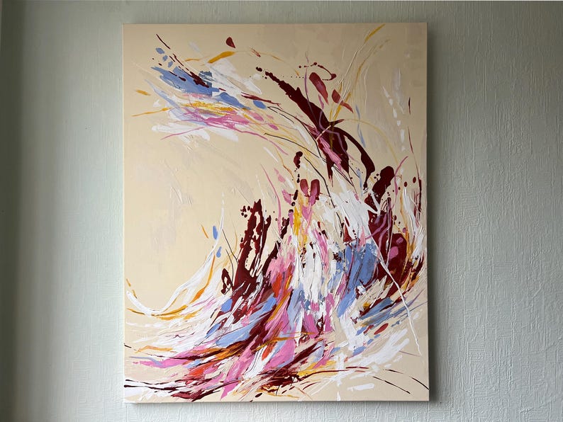 May include: Abstract painting on canvas with a beige background. The artwork features dynamic brushstrokes in shades of burgundy, white, blue, pink, and yellow. The composition is a vibrant display of color and movement, suitable for home decor.