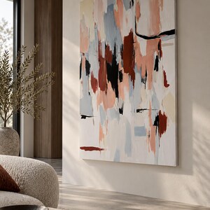 May include: A large rectangular canvas painting featuring an abstract composition of vertical brushstrokes in shades of terracotta, soft peach, pale blue, cream, and black against a white background, displayed on a wall in a living space.