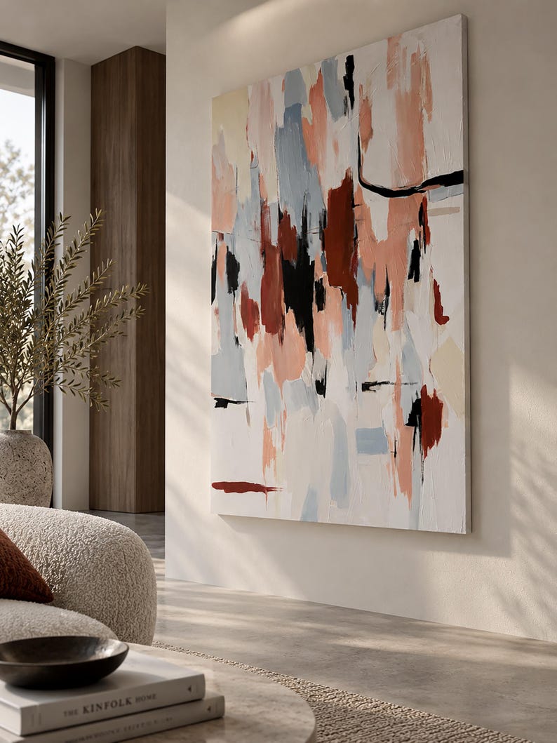 May include: A large rectangular canvas painting featuring an abstract composition of vertical brushstrokes in shades of terracotta, soft peach, pale blue, cream, and black against a white background, displayed on a wall in a living space.