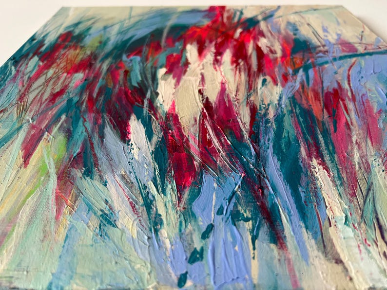May include: Abstract painting with a textured surface. The artwork features bold brushstrokes in shades of red, teal, blue, and white. The composition has a dynamic, energetic feel, with the colors blending and overlapping to create depth and movement.